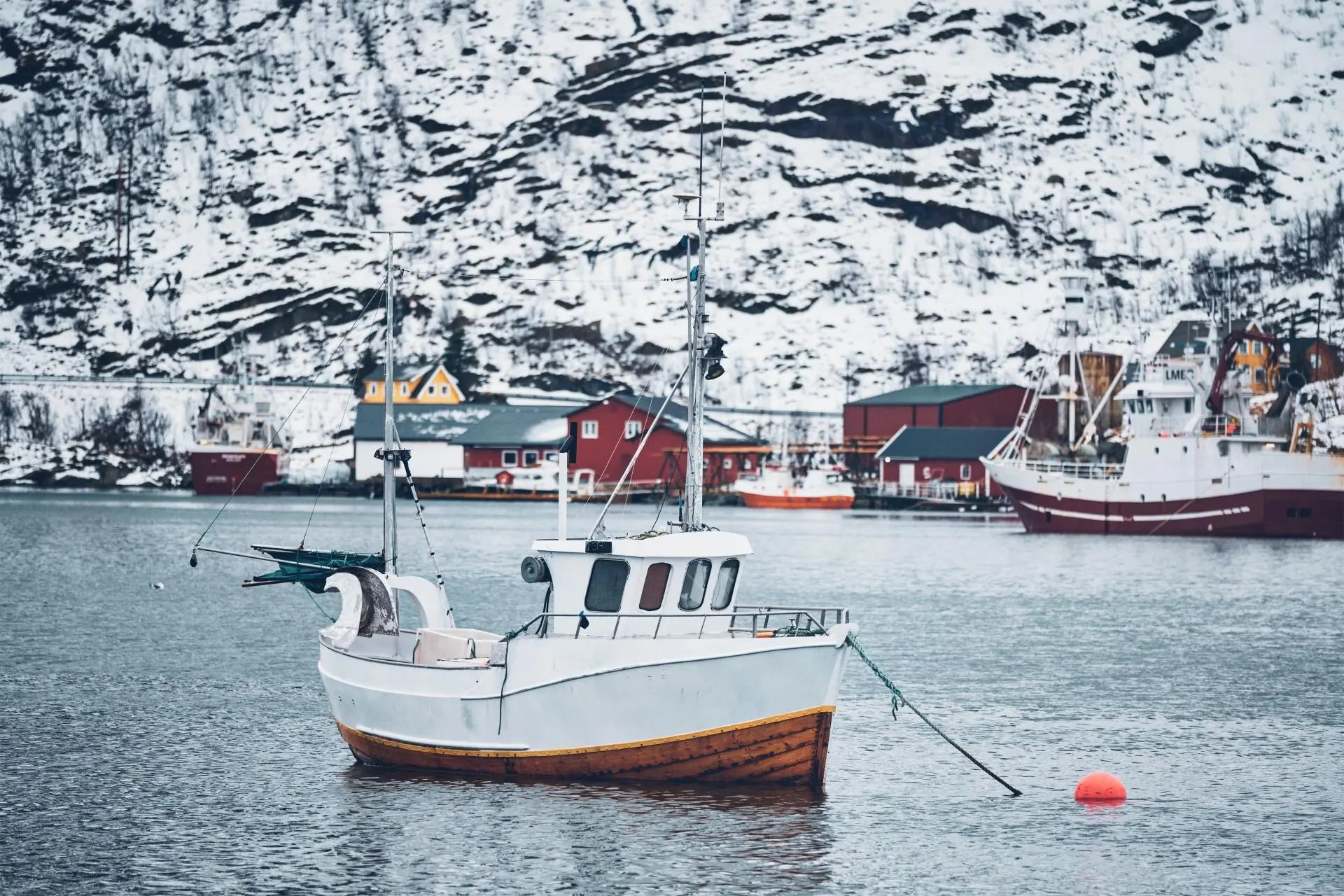 bateau-de-pecheur-dans-le-village-de-pecheurs-de-hamnoy-sur-les-iles-lofoten-en-norvege-avec-des-maisons-de-rorbu-rouge-avec-de-la-neige-qui-tombe